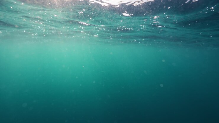 Underwater ocean swell showing the contrast between the moving water surface and the turquoise quiet of the depths below
