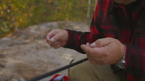 fisherman is choosing and fixing baits and lures on hook of rod closeup view of hands man is angling