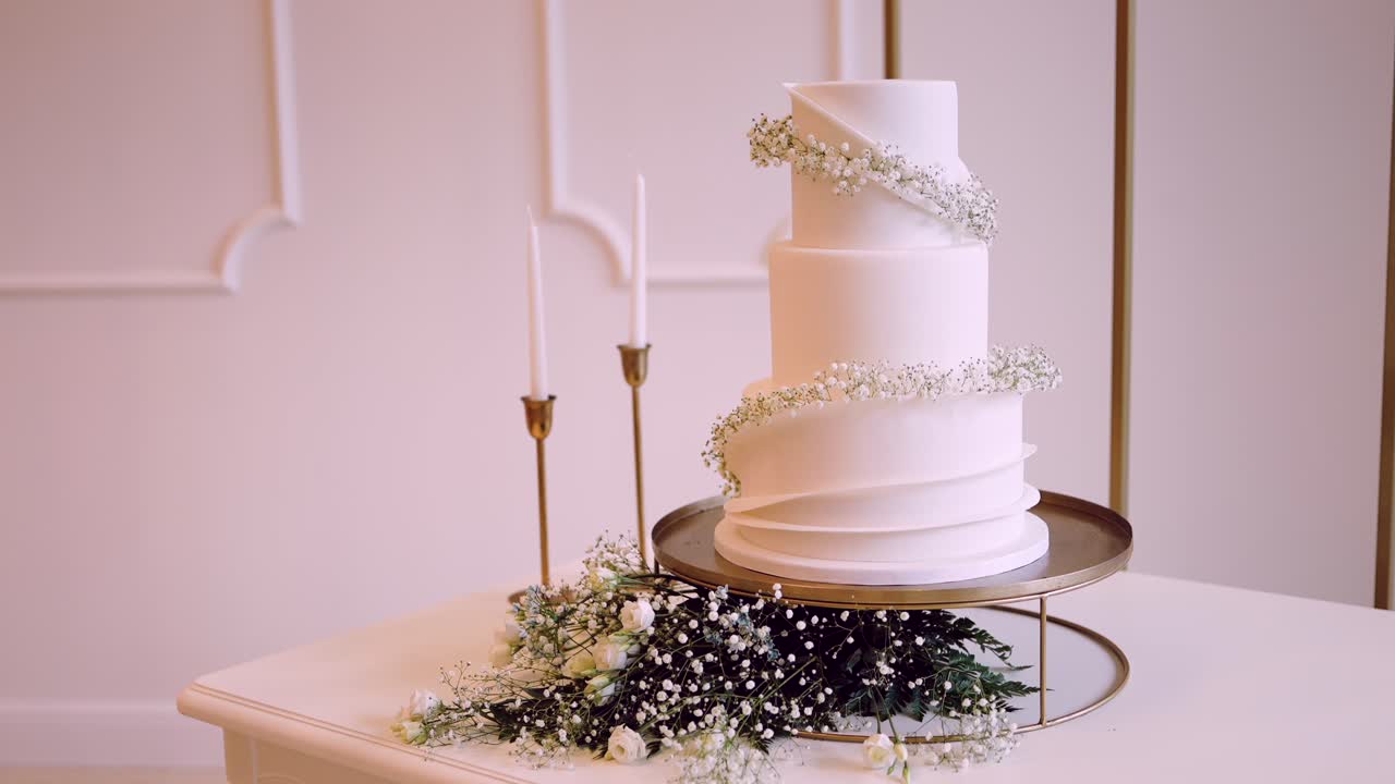 three tier white cake with delicate flowers and tall candles