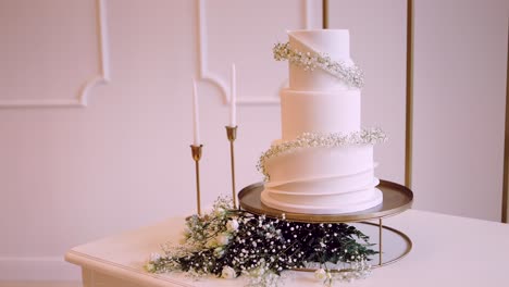 three tier white cake with delicate flowers and tall candles