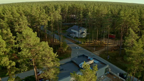 aerial drone forward moving shot over suburban area with beautiful private bungalows surrounded by dense green tree forest during eveing