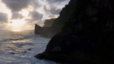 Silueta-De-Acantilados-Que-Revelan-El-Amanecer-Reflejado-En-Las-Olas-Del-Océano