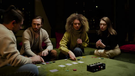 gruppe von freunden, die auf der couch im wohnzimmer poker spielen 4