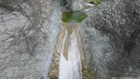 scenic small tropical stream waterfall in caribbean rainforest, aerial tilt down