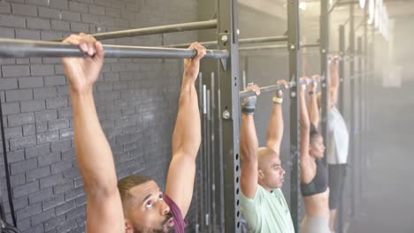 Diverse-group-fitness-class-training-at-gym-doing-pull-ups-on-bars,-in-slow-motion