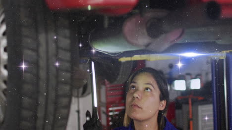 mechanic woman using led light inspecting undercarriage in auto repair garage with animated icons