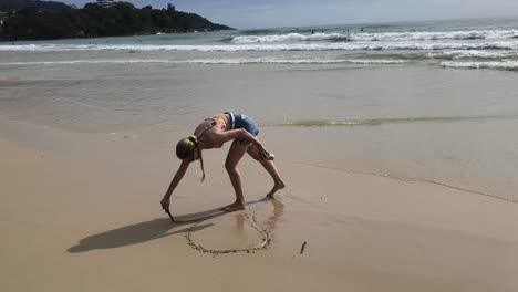 woman drawing a heart on the beach