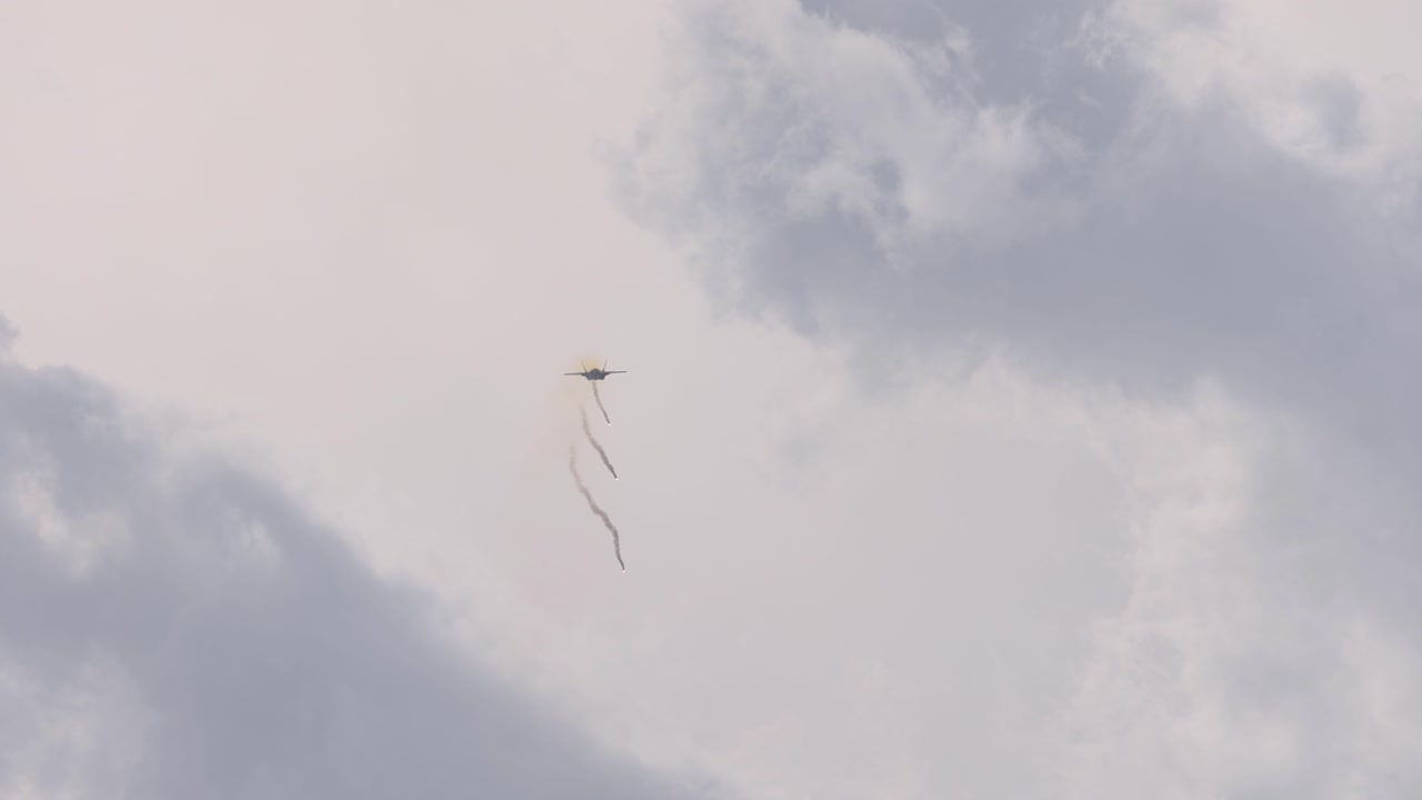 An F-35 jet releases flares during an aerial display against a cloudy sky at the Avalon Airshow