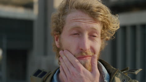 portrait handsome young man touching beard looking serious pensive caucasian male wind blowing hair slow motion