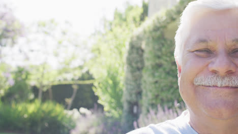 Half-face-portrait-of-happy-senior-caucasian-man-with-smiling-in-garden,-copy-space,-in-slow-motion