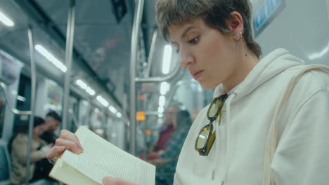 young woman reading a book during subway ride