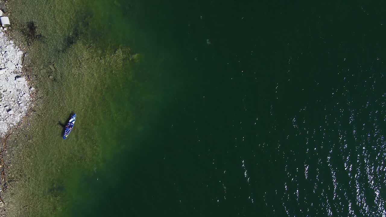 해안 가까이에 있는 블루보드에서 패들보드를 타는 사람의 넓은 공중 전망