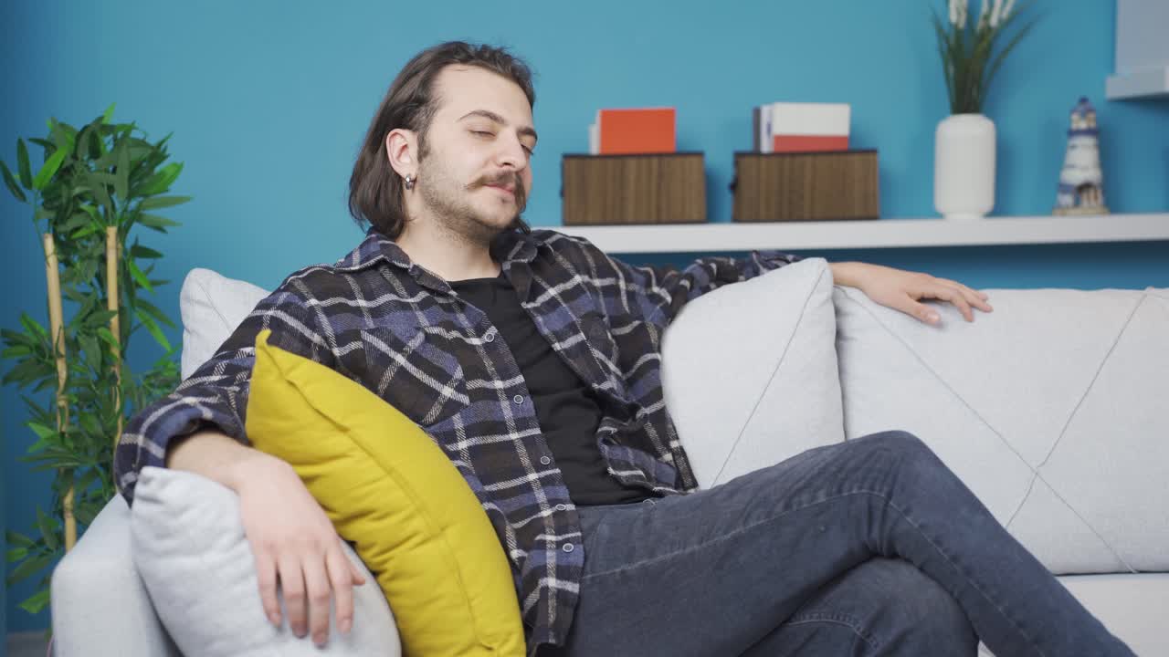 hombre descansando en casa, mira a la cámara y es positivo.