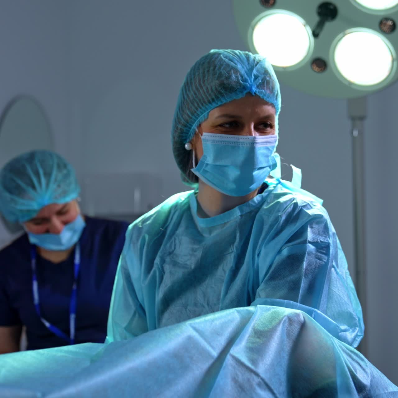 Female obstetrician wearing cap and mask checking the patient. Smiling doctor talks to the lady under examination. IVF procedure in clinics