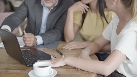 cropped view of confident colleagues sitting at table