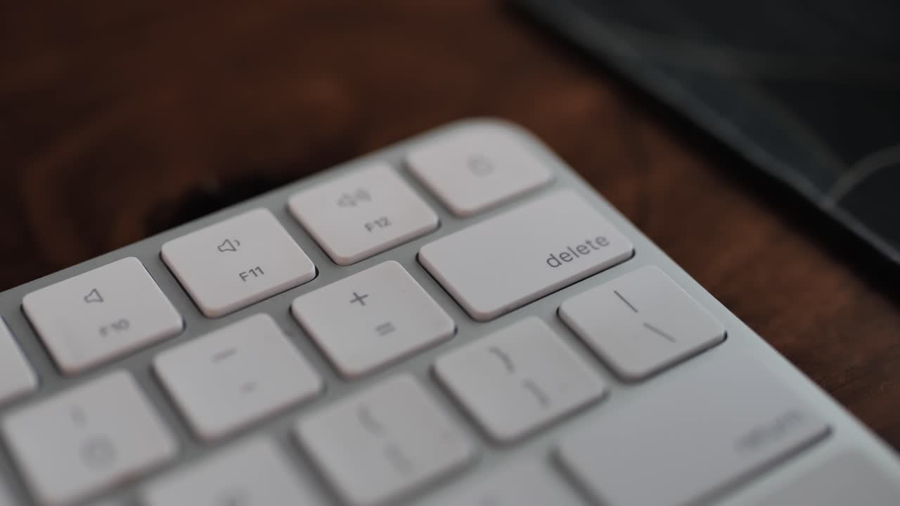 Man hand pressing delete button on a white keyboard