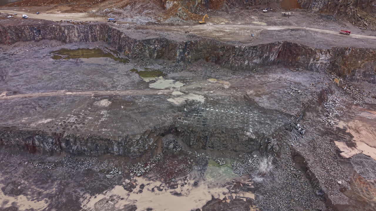 Cava di granito in funzione con macchinari pesanti e veicoli al lavoro sul posto, che mostra grandi formazioni rocciose in un'area di costruzione