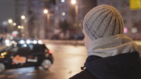 Noche-Fría-En-La-Ciudad,-El-Hombre-Observa-El-Tráfico-En-La-Carretera,-Vista-Desde-Atrás