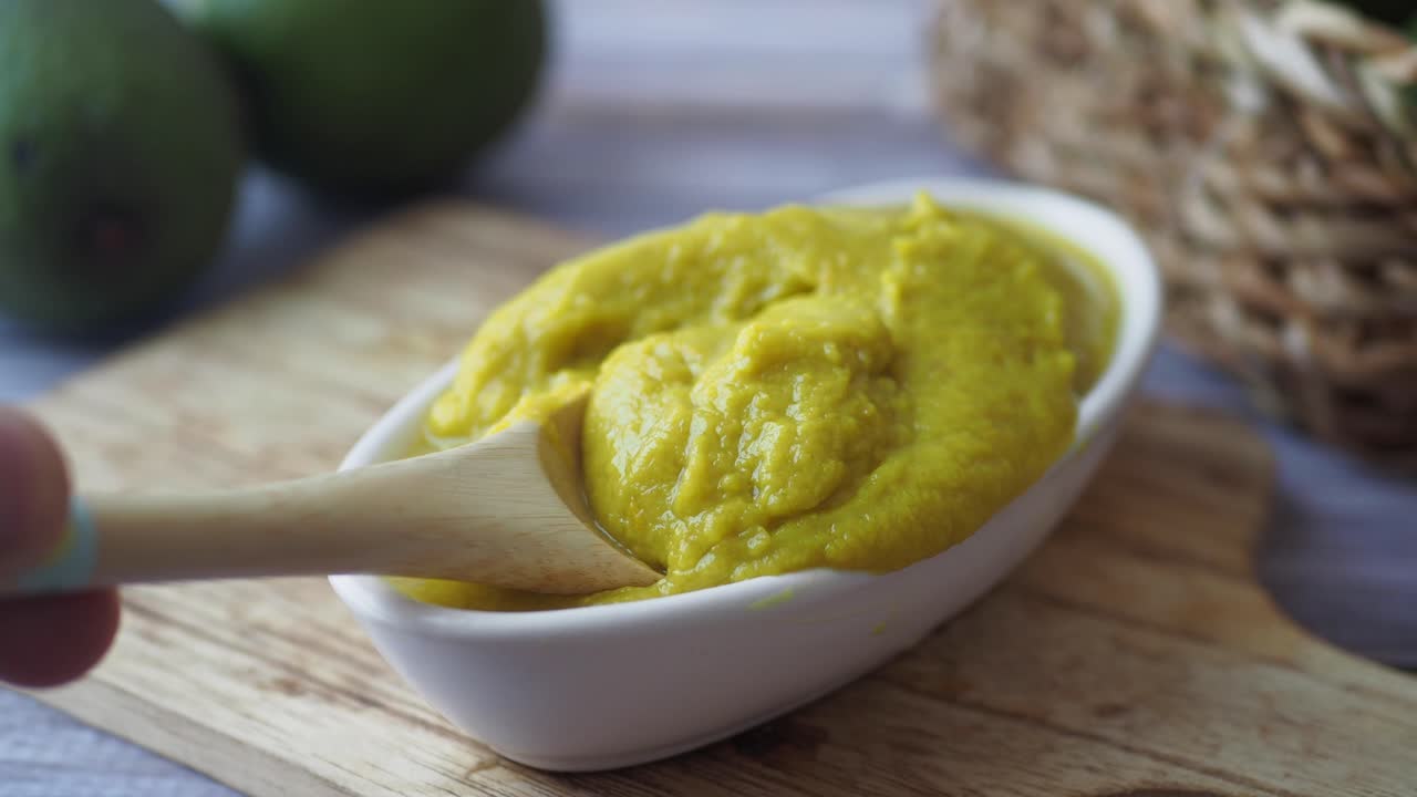 Close-up of a bowl of mango chutney with a wooden spoon