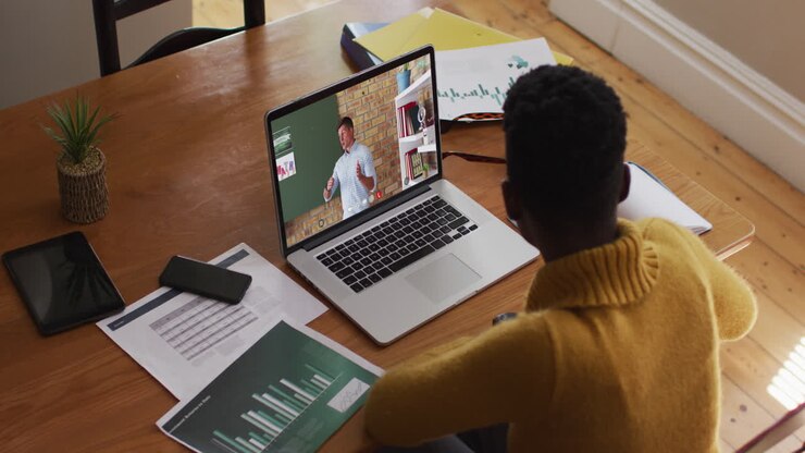 Studentessa afroamericana che usa un laptop in videochiamata con un insegnante uomo.
