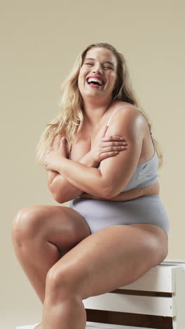 vertical video: smiling plus size woman in underwear embracing body positivity,