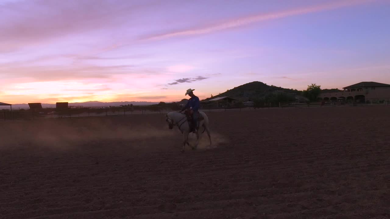 As the Arizona sunsets, a cowboy is still working his horse in the corral, Queen Creek, Arizona