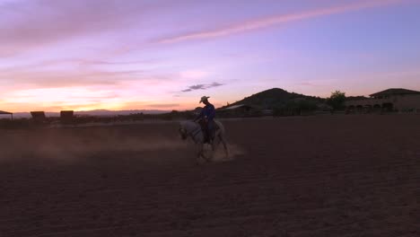 as the arizona sunsets, a cowboy is still working his horse in the corral, queen creek, arizona