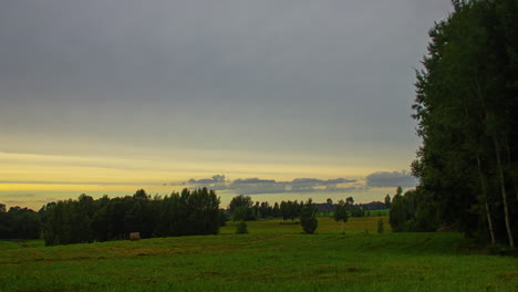 a time lapse shot of a green grassy landscape under a wind shear at sunset