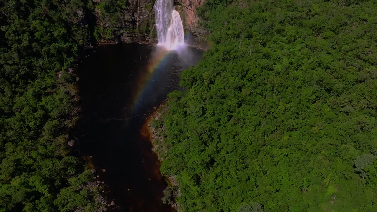 Aerial view of Cachoeira dos Saltos waterfall forming a rainbow over Rio Preto in Chapada dos Veadeiros National Park, a UNESCO World Heritage site located in Brazil, drone revealing shot