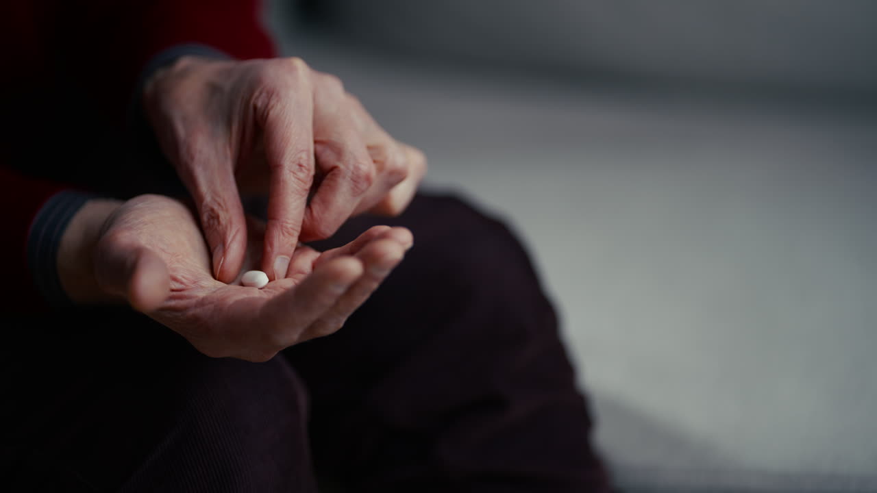 Primo Piano delle Mani di una Persona Anziana che Tengono una Pillola Bianca