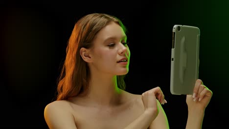 young woman interacting with a tablet with colored lighting
