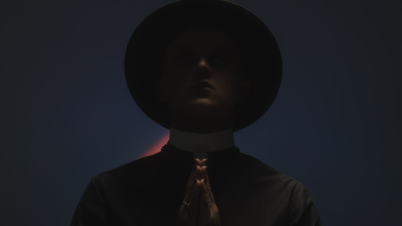 Man in Priest Costume Posing with Palms Together