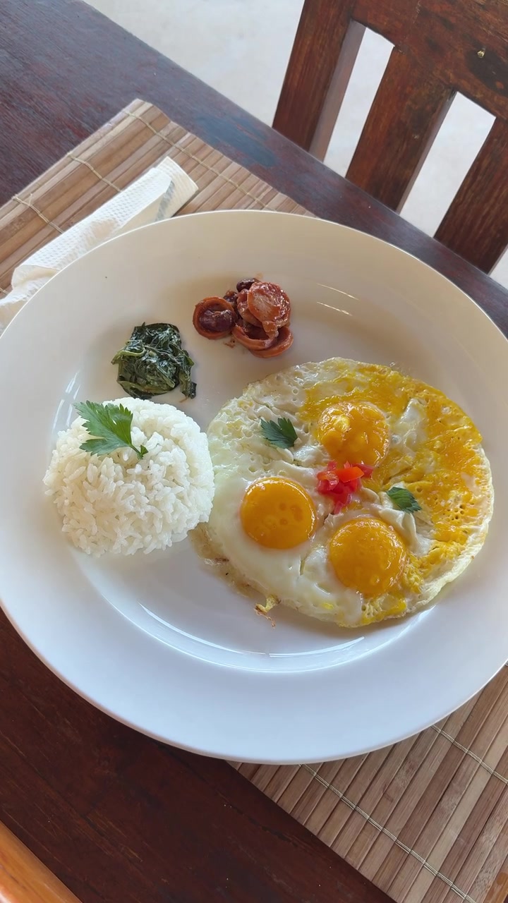 Delicioso plato de desayuno con huevos fritos, arroz, salchicha y espinacas