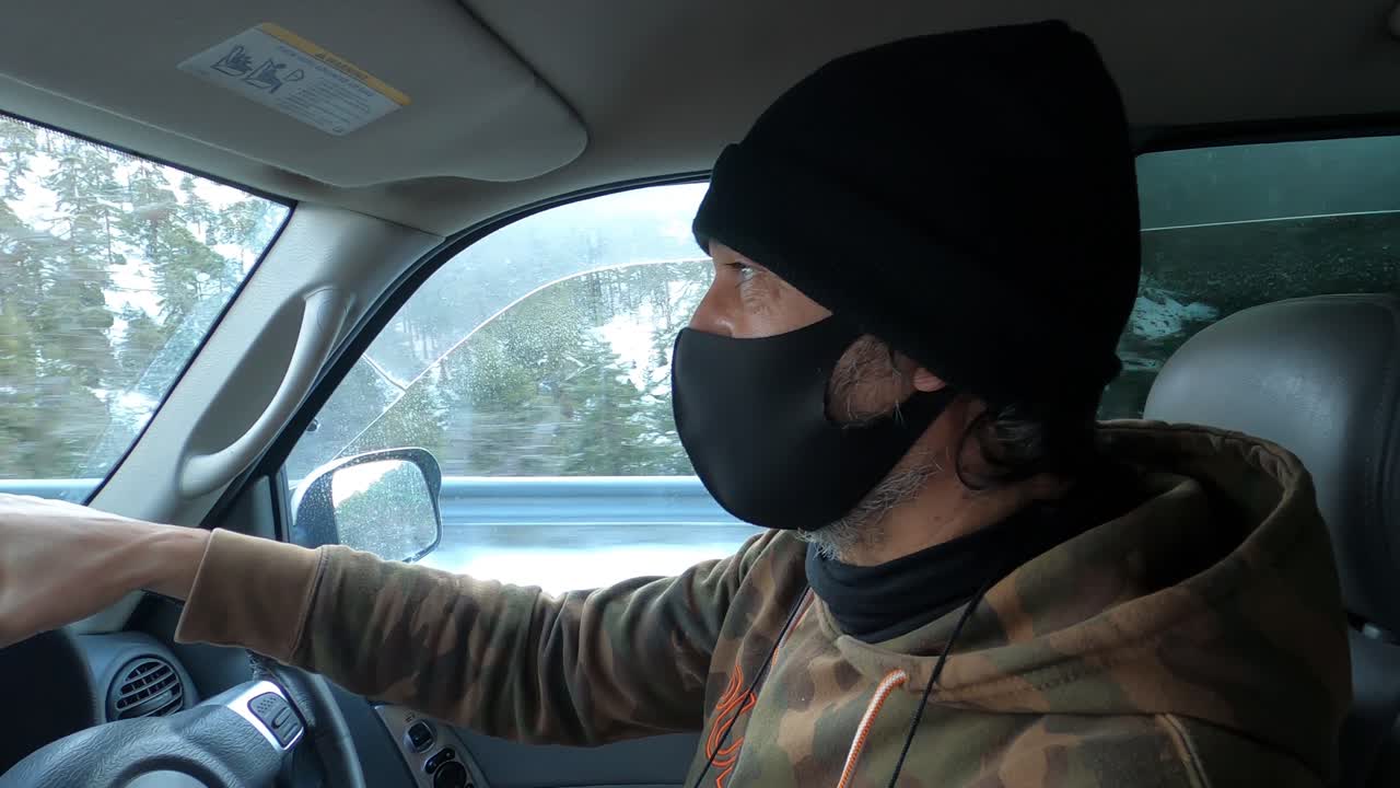 covid-19 대유행 동안 눈 속에서 운전할 때 천 마스크를 쓴 남자가 있는 자동차 내부