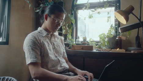 asian man working on laptop in antiques shop