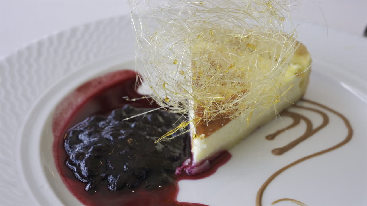 Close up of a piece of cheesecake with blueberry sauce on a white plate