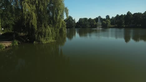 Dynamische-Drohnenaufnahme-Eines-Sees-Mit-Springbrunnen-Im-Niedrigen-Winkel