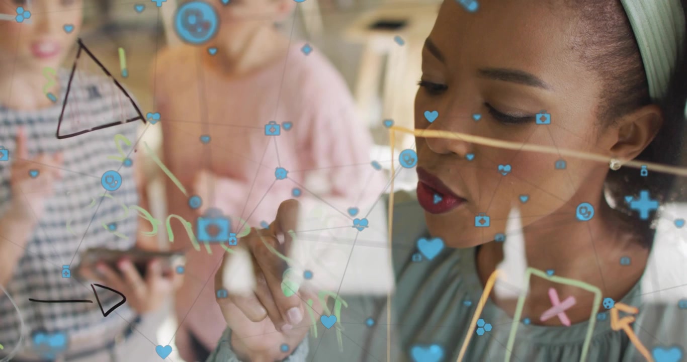 Designer picking up green marker sketching icons and arrows on glass surface for business meeting