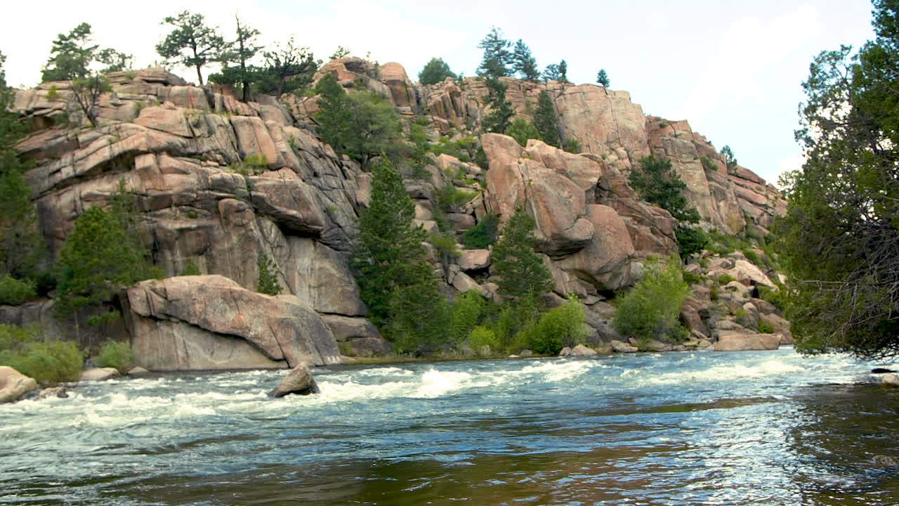 a white water stream flowing past a rock cliff