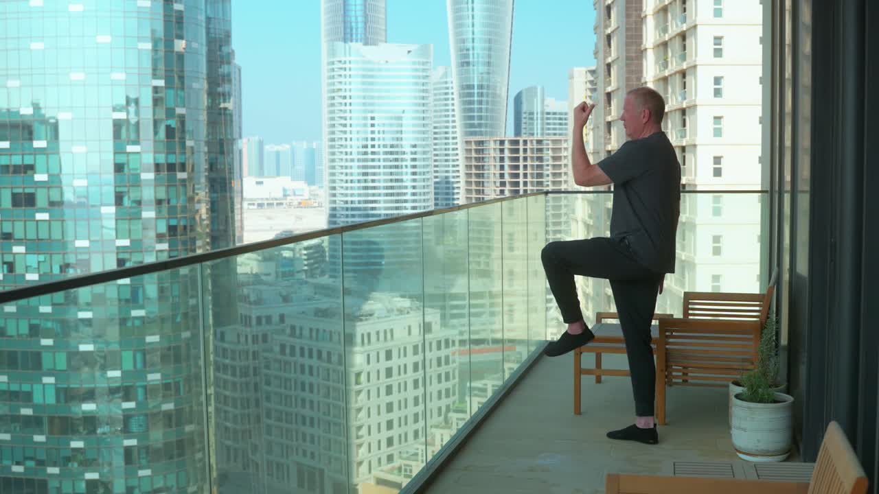 Tai Chi - Elder man alone on an urban balcony with a city skyline background as part of a healthy and balanced morning routine