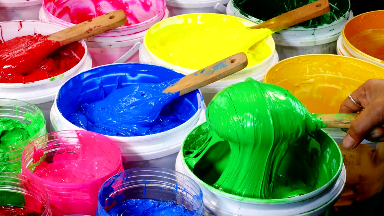 Colored wooden spoon used for scoop paint buckets.