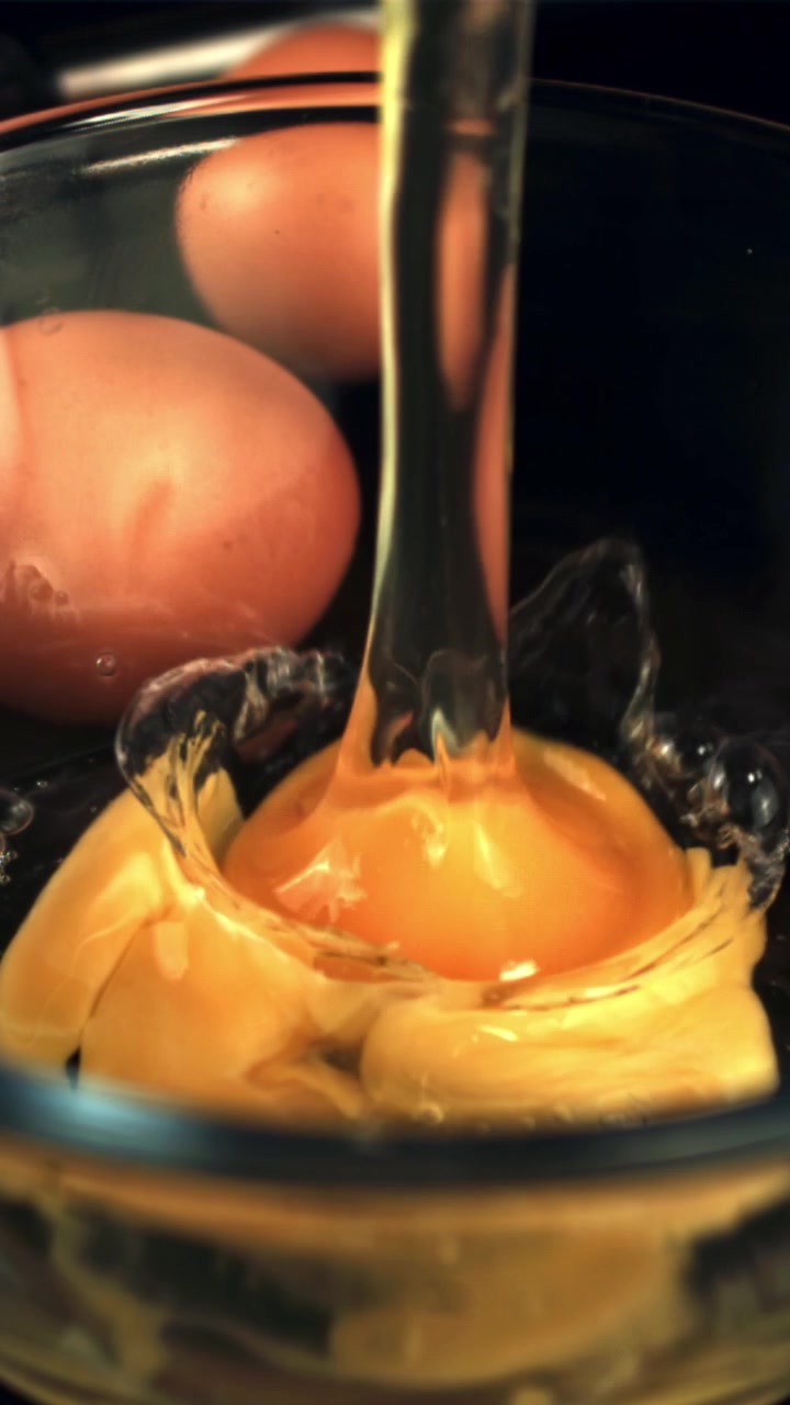Slow Motion of Fresh Eggs Being Cracked into a Glass Bowl