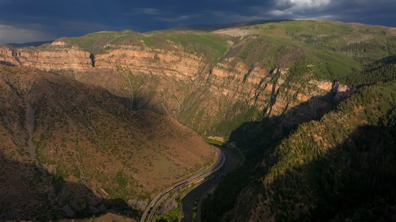 Summer Glenwood Canyon Scenic Drive Glenwood Springs Colorado River interstate i70 highway west east car traffic sun on Grand Mesa cliffside late afternoon dark rain thunderstorm cloud backward pan