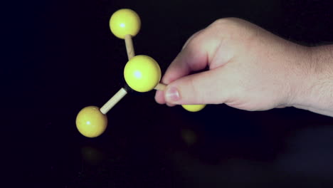 ball and stick model of methane being moved around on a black lab bench