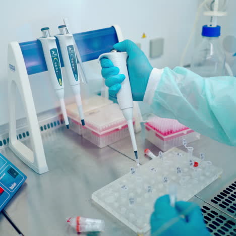 laboratory assistant working with vials. female worker in protective gloves filling test tube with liquid in the research laboratory.