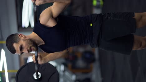 hombre musculoso entrenando con barra, haciendo sentadillas en el gimnasio