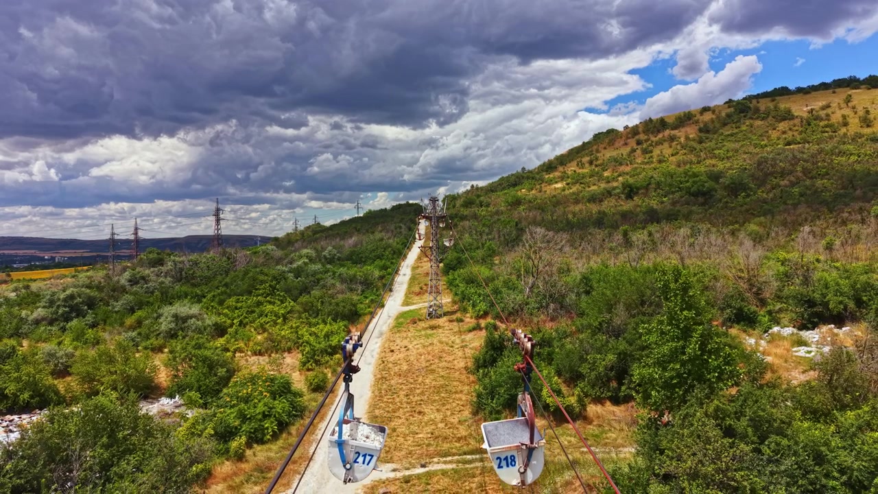 Zipline dráha se táhne přes svah se stromy a zataženou oblohou v pozadí během dne v rekreační oblasti.