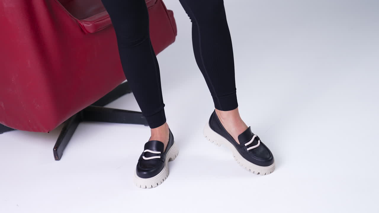 Modern black shoes on white tractor soles performing. Model in black pants demonstrates fashionable stylish shoes. Close up.