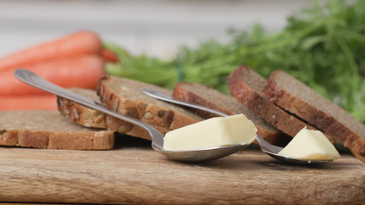 Wooden cutting board with slices of wholemeal bread and two servings of butter