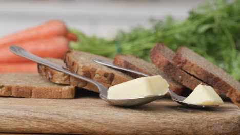 wooden cutting board with slices of wholemeal bread and two servings of butter